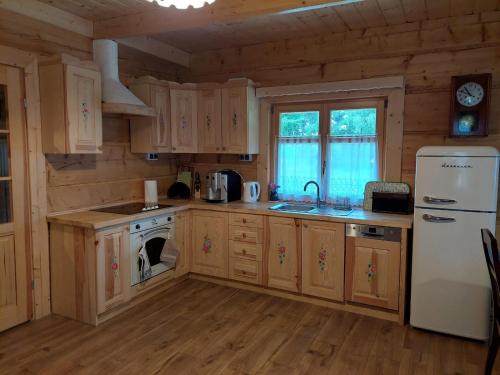 een keuken met houten kasten en een witte koelkast bij Domek u Heli in Limanowa