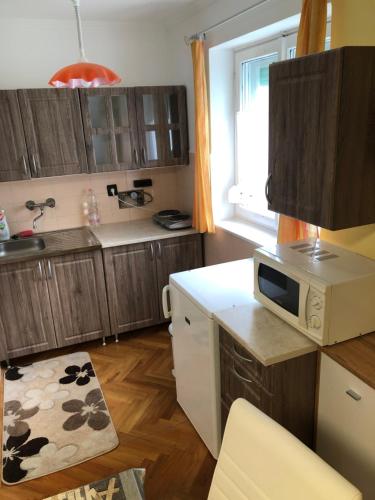 une cuisine avec des placards en bois et un four micro-ondes sur un comptoir dans l'établissement BB apartman, à Harkány