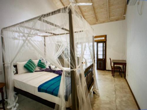 a bedroom with a canopy bed and a table at Silva Rest in Unawatuna