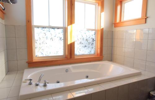 a bath tub in a bathroom with two windows at Harbourview Inn in Smiths Cove