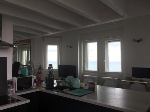uma cozinha com 2 janelas e uma mesa com um micro-ondas em 1ère ligne Mer Appartement 7 personnes. em Biarritz