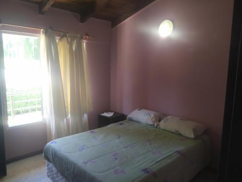a small bedroom with a bed and a window at Departamentos La Gringa in El Bolsón