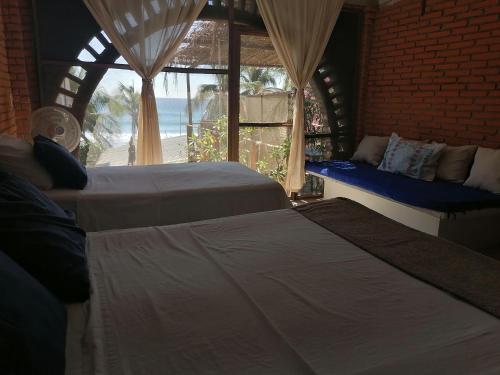 twee bedden in een kamer met uitzicht op de oceaan bij Posada Casa San Agus in San Agustinillo