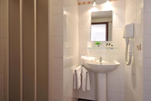 Baño blanco con lavabo y espejo en Hôtel du Perron, en Theux