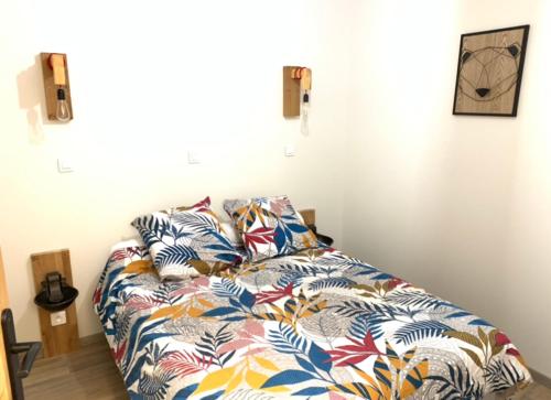 a bed with a colorful comforter in a room at Gîte le BISTANCLAC. in Charlieu