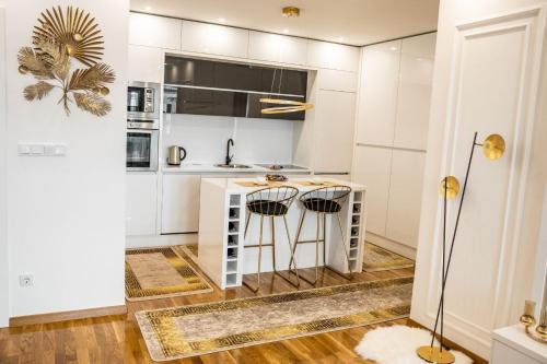 a kitchen with white cabinets and a counter with stools at Luxury Apartment Karic FREE parking in Tuzla