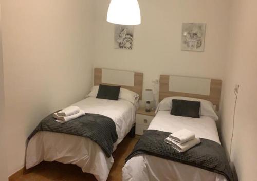 two beds in a small room with towels on them at Cortijo Mazarrón in Güéjar-Sierra