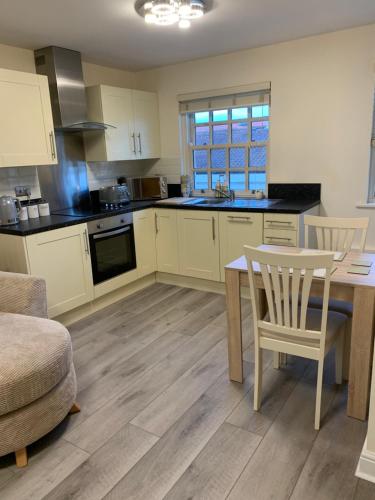 a kitchen with white cabinets and a table and chairs at 2 Bedroom duplex apartment in Bawtry