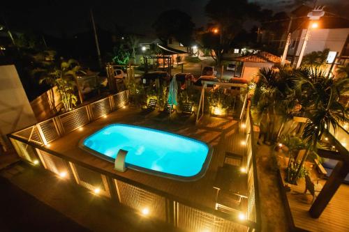 una piscina al aire libre por la noche con luces en Pousada Cacau, en Praia do Rosa