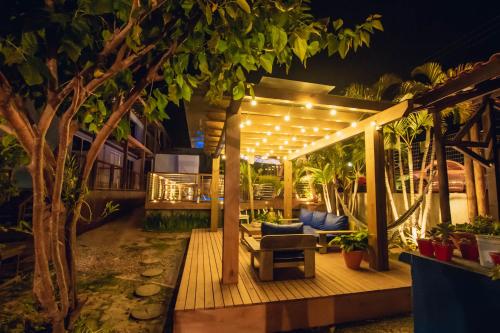 a pergola with a couch and chairs on a deck at Pousada Cacau in Praia do Rosa