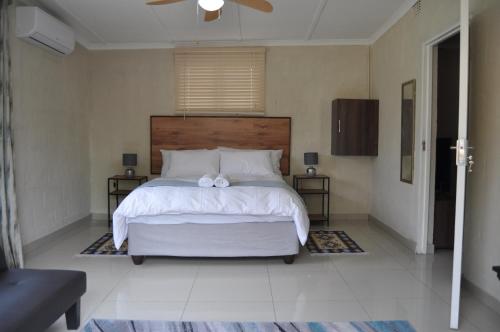 a bedroom with a large white bed with a bow on it at Kosi Khaya in Manguzi