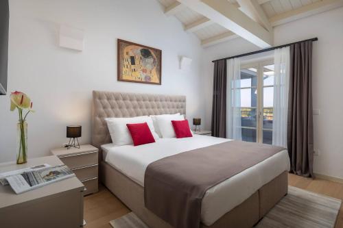 a bedroom with a large bed with red pillows at Villa Alicia by ILC (Istria Luxury Collection) in Brtonigla