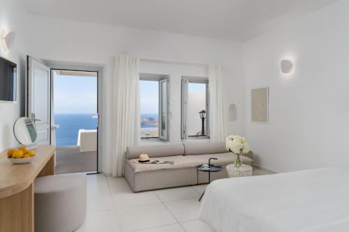 a white room with a bed and a room with the ocean at Lilium Hotel Santorini in Fira