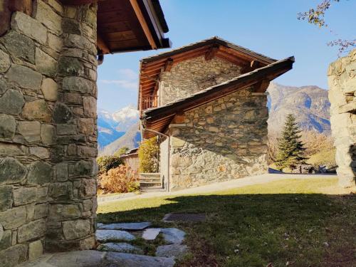 an entrance to a stone building with mountains in the background at La Majon de Fohten in Montjovet