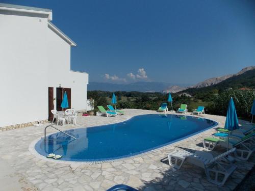 a swimming pool with chairs and umbrellas on a patio at Villa Maja in Baška