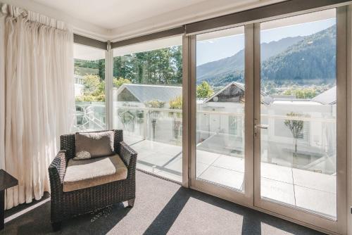 a room with sliding glass doors and a chair on a balcony at Blue Peaks Apartments in Queenstown