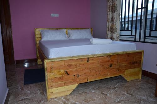 Cama de madera en habitación con ventana en Lunguya Annex Lodge, en Dar es Salaam