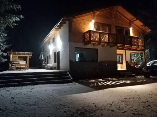 ein Haus mit einer Veranda und einem Balkon in der Nacht in der Unterkunft Four Season Komando in Comandău