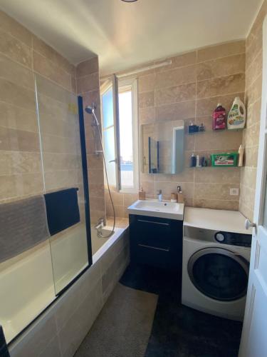 a bathroom with a sink and a washing machine at Grande chambre privative à 20 minutes de Paris in Colombes