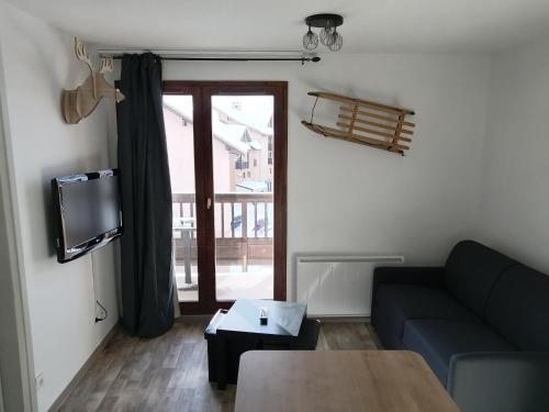 een woonkamer met een bank en een tv bij APPARTEMENT VALMEINIER 1800 / RESIDENCE L'OURS BLANC in Valmeinier