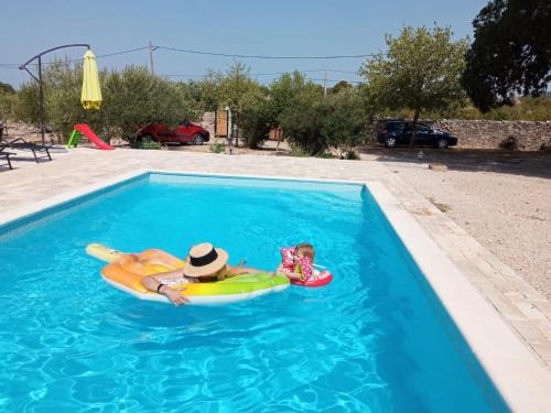 a woman and a child on a raft in a swimming pool at Marcelovi dvori in Pirovac