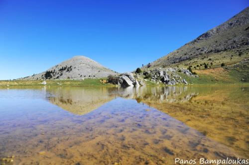 a mountain reflection in the water of a lake at St. John Traditional House in Áyios Ioánnis