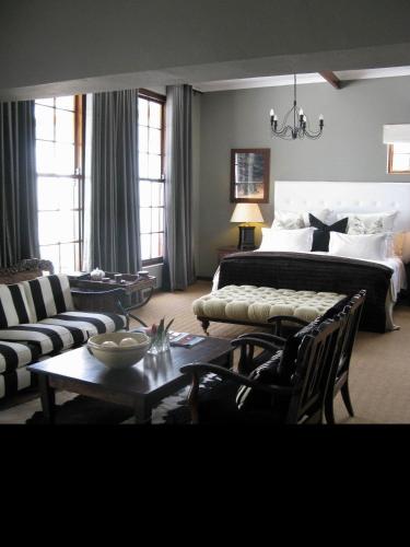 a bedroom with a bed and a couch and a table at Lairds Lodge Country Estate in Plettenberg Bay