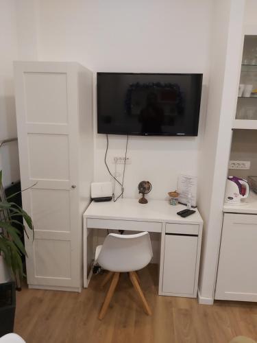 a white desk with a chair and a television on a wall at ZAGRABY APARTMENT in Zagreb