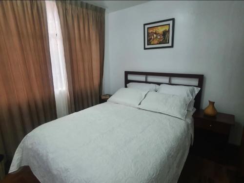 a bedroom with a white bed and a window at Depa Céntrico, cerca a todo! in Cajamarca