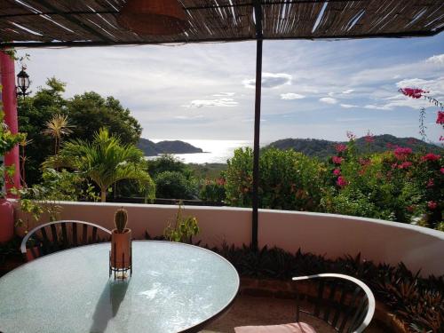 uma mesa de vidro e cadeiras numa varanda com vista em El Jardin em San Juan del Sur