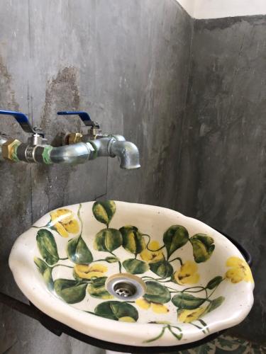 a bathroom sink with leaves painted on it at El Garzal in Mercedes