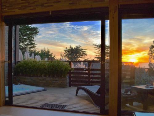 a screened in porch with a sunset in the background at ---- ESCAPADA DE LUJO PARA DOS ---- Casa Boutique Privada - Vistas al Océano - Parrilla y Fogón en Quincho Privado - Insumos desayuno - Tu estadía incluye GRATIS 1 Sesión de Hidromasaje & Cromoterapia bajo las estrellas en Jacuzzi Privado in Pichilemu