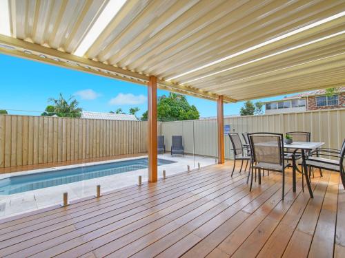 a deck with a table and chairs and a swimming pool at Sea Renity in Bonny Hills