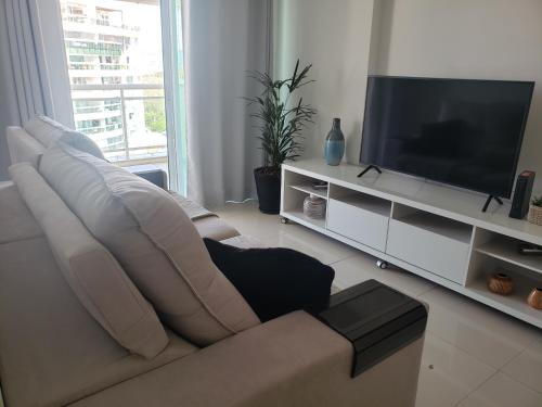 a living room with a couch and a flat screen tv at Condomínio Encantador (Blue das Americas) in Rio de Janeiro