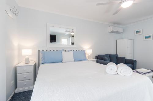 a bedroom with a white bed and a blue couch at Debbie's Place in Rainbow Beach