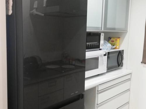 a kitchen with a black refrigerator and a microwave at Room Biotop YOMITAN in Yomitan