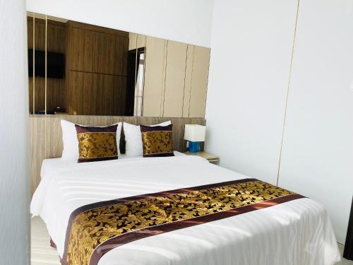 a bedroom with a large white bed with brown pillows at Aurora Western Village in Ho Chi Minh City