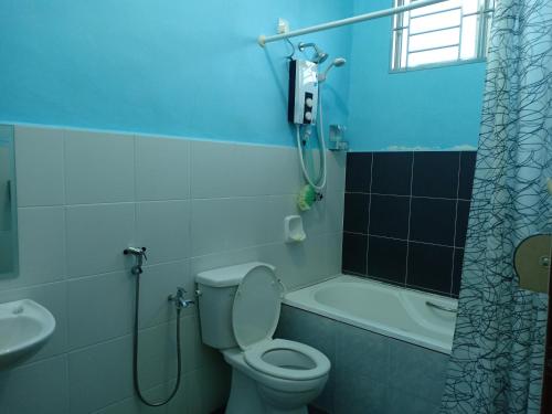 a bathroom with a toilet and a shower and a sink at Mutiara Desaru Cottage in Bandar Penawar