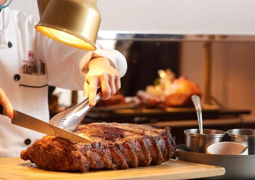 a chef is cutting a steak with a knife at The Howard Plaza Hotel Taipei in Taipei
