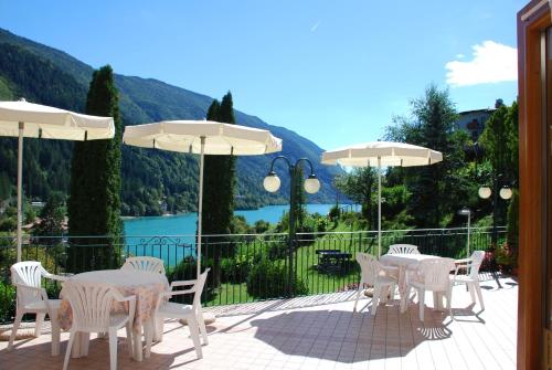 a patio with white tables and white chairs and umbrellas at Charme Hotel Nevada in Molveno