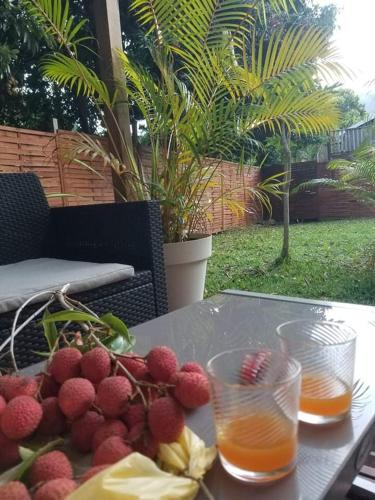 un tavolo con un piatto di frutta e due bicchieri di succo di Bunga-lodge VANILLE a Saint-André