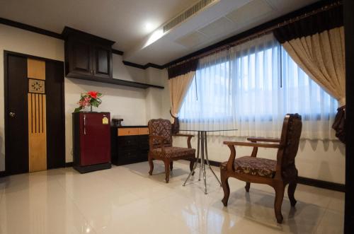 a living room with a table and chairs and a window at Chiangrai Grand Room Hotel in Chiang Rai