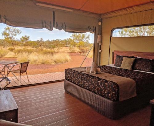 a bedroom in a safari tent with a bed and a patio at Karijini Eco Retreat in Karijini