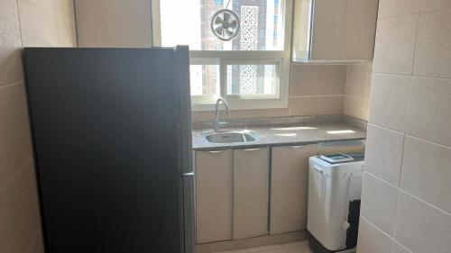 a small kitchen with a refrigerator and a sink at BAITI Furnished Apartments in Salalah