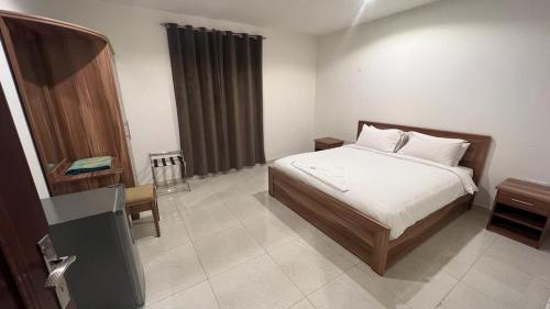 a bedroom with a bed and a dresser and a table at BAITI Furnished Apartments in Salalah