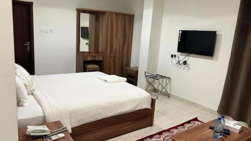 a bedroom with a bed and a flat screen tv at BAITI Furnished Apartments in Salalah