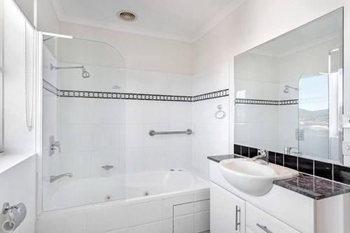 a white bathroom with a sink and a bath tub at 814 Shoal Bay Waterviews in Shoal Bay