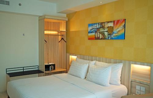 a hotel room with a bed with white pillows at Swiss-Belhotel Makassar in Makassar