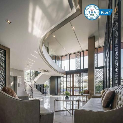 a lobby with chairs and a spiral staircase in a building at Zayn Hotel Bangkok - Airport Link Access in Bangkok