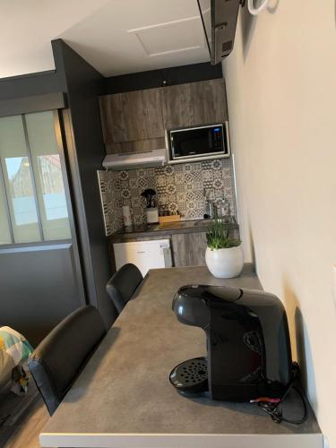 une petite cuisine avec une table et un micro-ondes dans l'établissement Le Petit Chaleureux - Centre ville - Wifi - stationnement (idéal couples, étudiants, business), à Niort